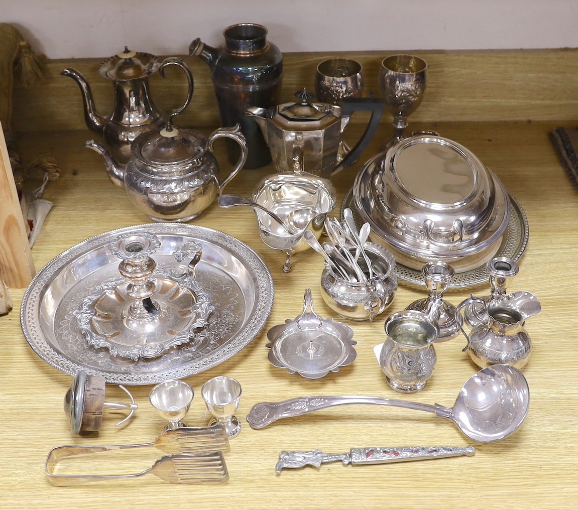 A quantity of assorted plated wares including a chamberstick, a tea set, flatware, a cocktail shaker, a sauceboat, goblets, etc.